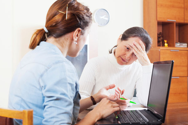 A mental health professional talking to a patient in a therapy session with a laptop, showing the use of closed-loop reporting