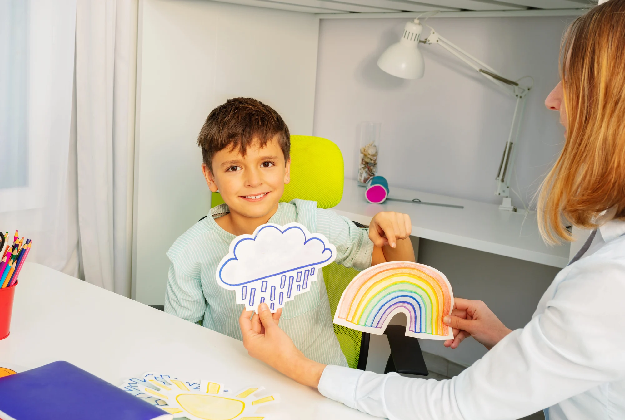 boy showing a rainbow drawing at an aba therapy center