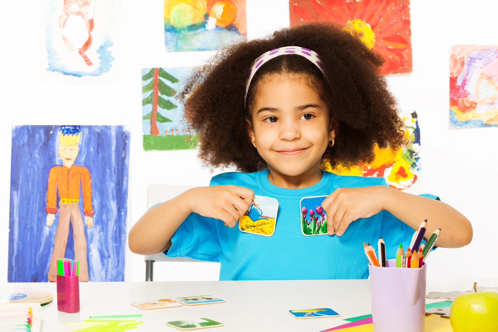 girl poses with educational cards in her hands at an ABA therapy center