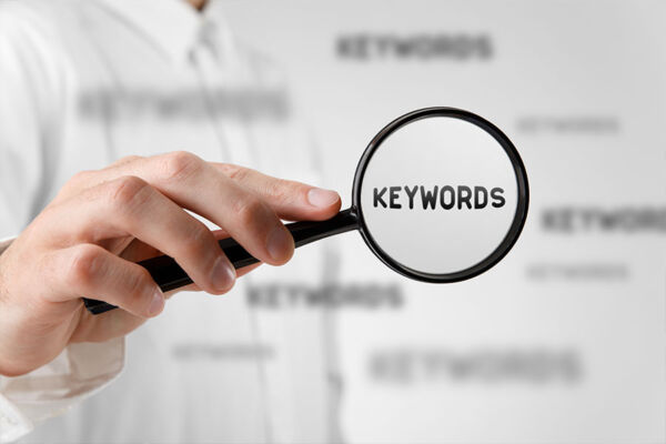 Man holding a magnifying glass conceptually highlighting the word 'keyword' in search engine optimization (SEO) research.