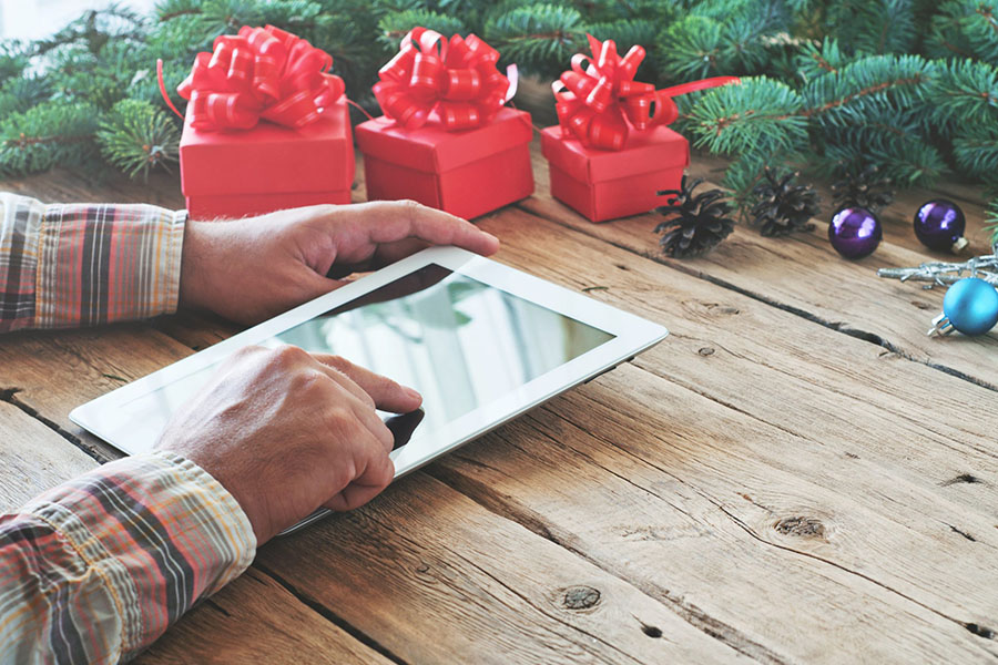 Man using tablet around christmas decorations concept image for pause PPC for the holidays.