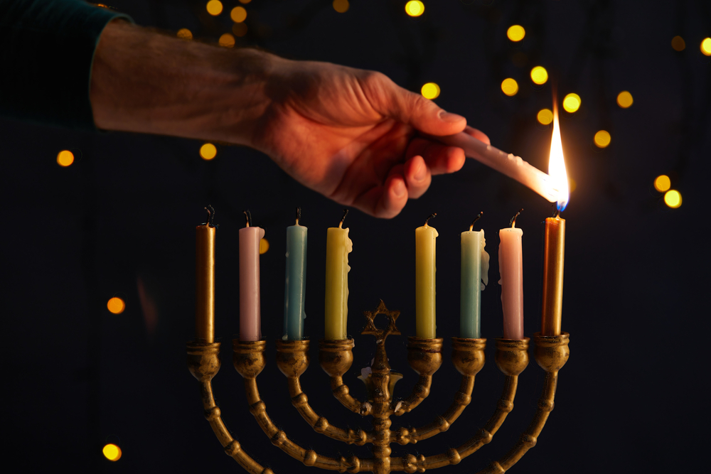 Jewish drug rehab marketing: Partial view of man lighting up candles in menora